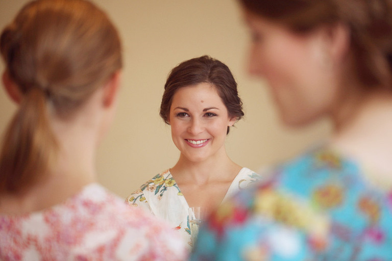 A bride smiles at her bridesmaids while getting ready for her wedding at the Woodstock Inn in Woodstock, VT. 