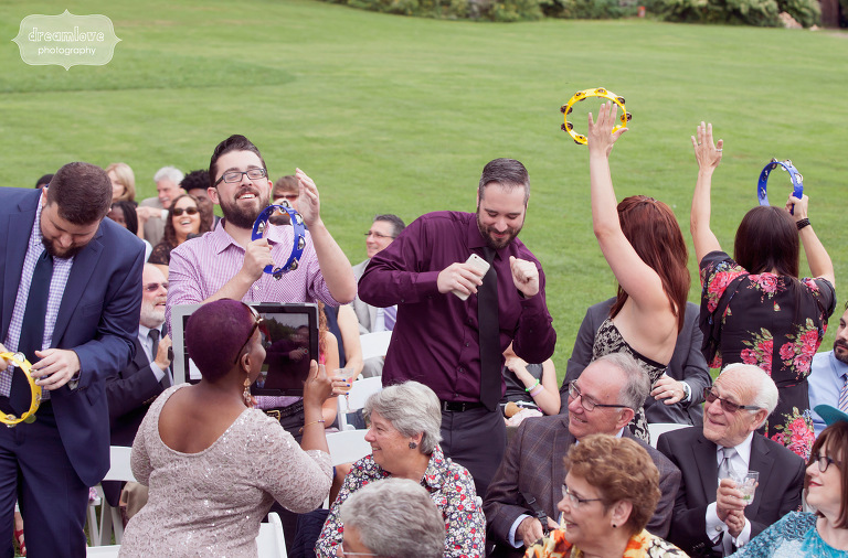 Wedding guests danced and play tambourines as the bride and groom walked down the aisle together. 