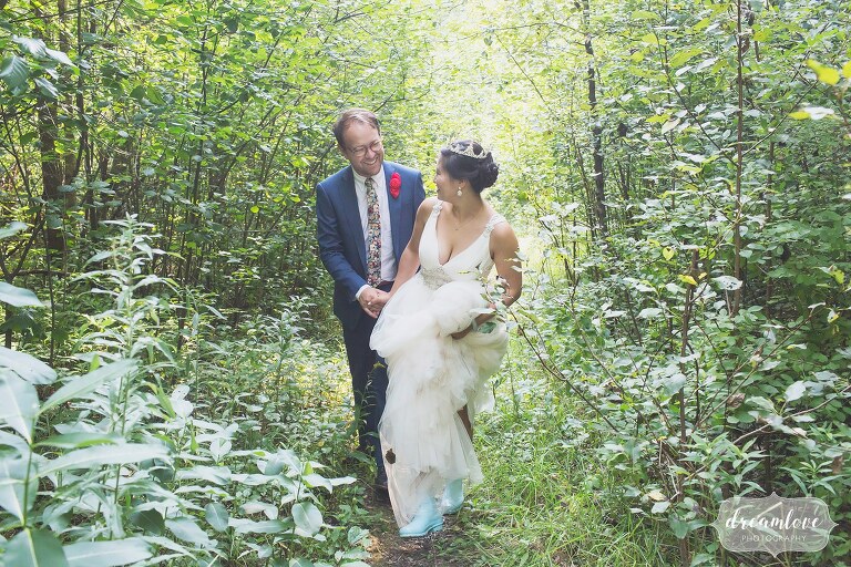 Bride and groom walk through a field in hunter blue boots.