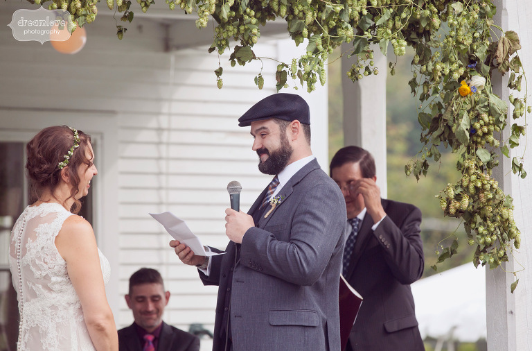 A happy couple read their vows while surrounded by a floral arrangement during their back porch wedding. 