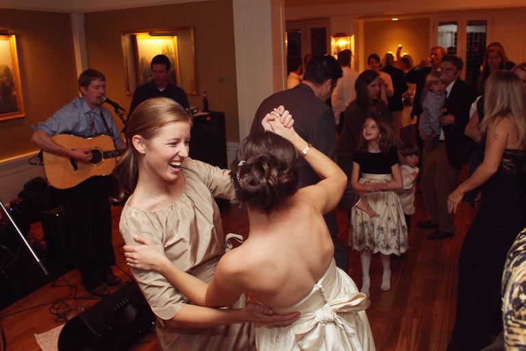 A bridesmaid and bride dance together to live music in Rockefeller Room at the Woodstock Inn.