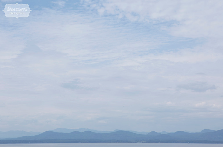 stunning landscape with green mountain range over lake champlain from the shelburne farms wedding venue