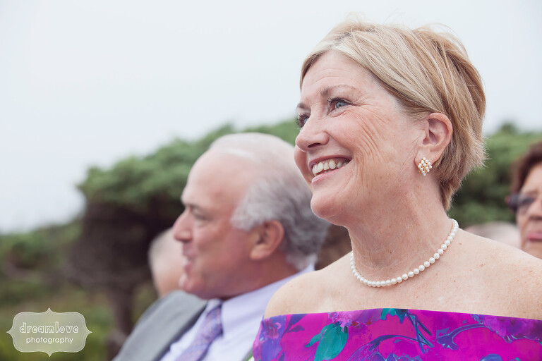 Candid wedding photo of the groom's mother watching the beach ceremony on the Cape.