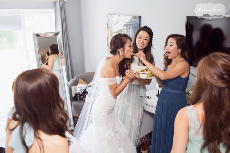 Funny documentary wedding photo of the bridesmaids feeding the bride french fries before the wedding in Wolfeboro, NH.