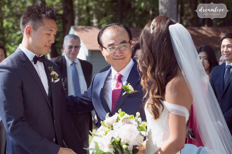 The father of the bride gives his daughter away at this Korean wedding ceremony on the lake in Wolfeboro, NH.