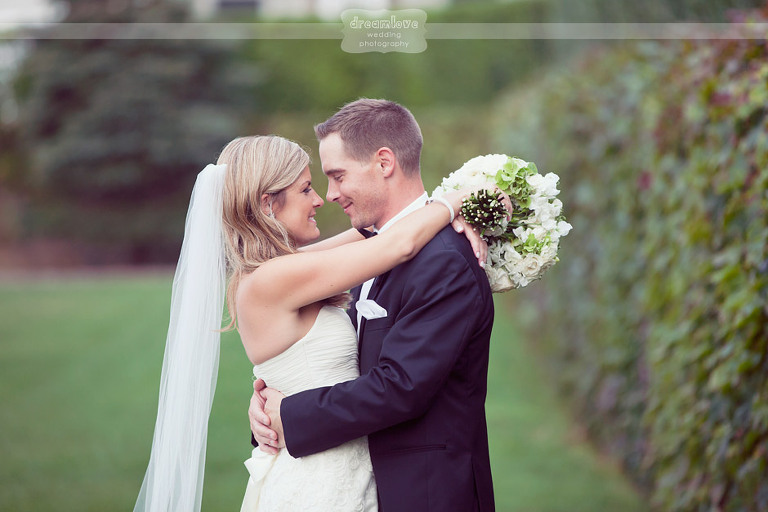Smiling couple on their wedding day surrounded by the lush hedgerows at the Wychmere Beach Club. 