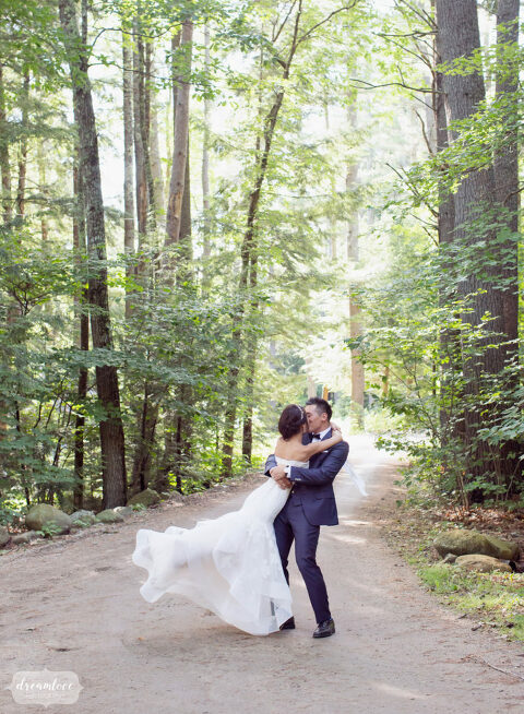 This woodland wedding photo of the bride and groom swinging around under the trees in Wolfeboro, NH is magical.