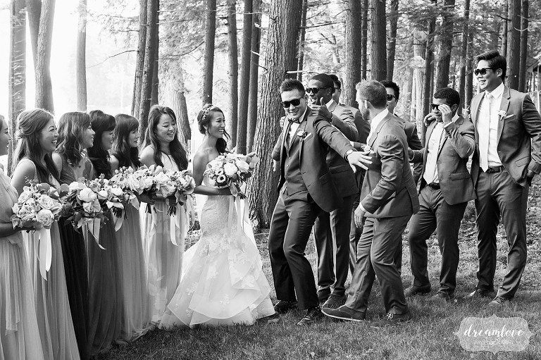 Funny wedding photography of the groom pretending to hold groomsmen back from his bride in Wolfeboro, NH.
