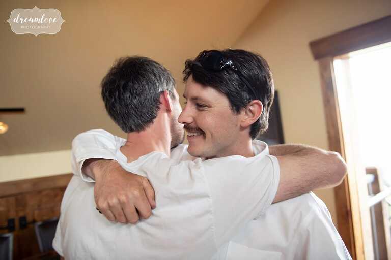 Groomsmen hugging at CO mountain ranch wedding.
