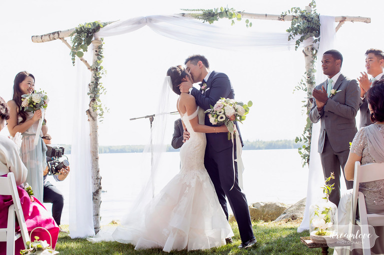 The bride and groom have the ceremony kiss in this natural wedding photo.