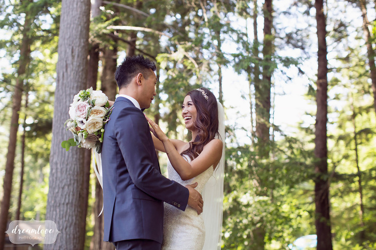 Nature style wedding photography of the bride laughing at the groom surrounded by pine trees in Wolfeboro.