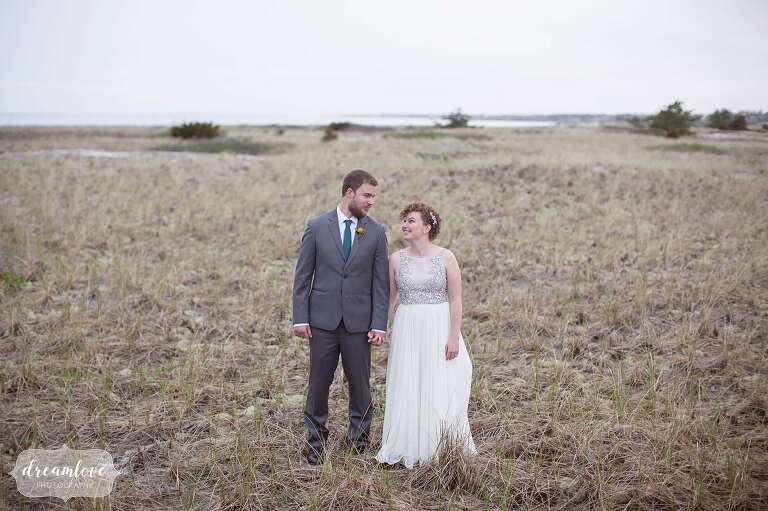 Bride and groom stand on Merkel Beach next to the Wychmere wedding venue on Cape Cod.