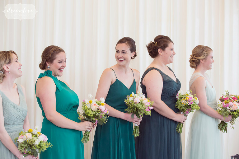 Beach wedding with bridesmaids in various shades of green dresses.