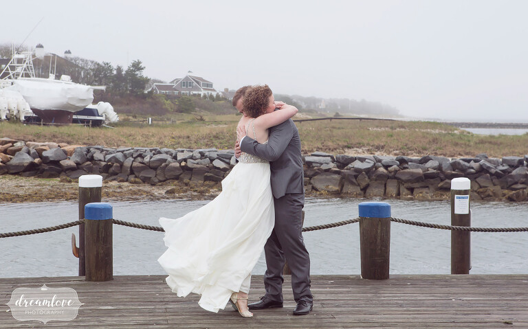 The bride and groom hug each other on the dock in Harwich, MA on the Cape before their rustic beach wedding.