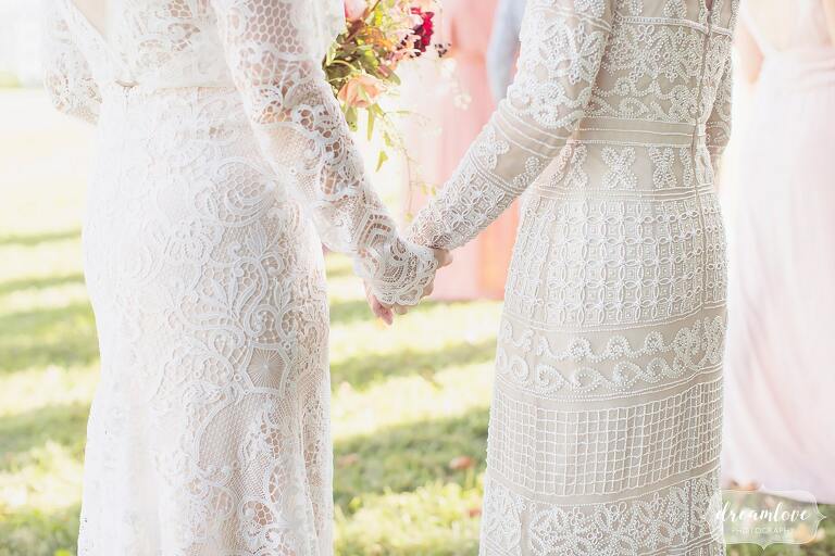 The bride and her mother hold hands while wearing embroidered lace and beaded dresses for a September wedding in Ghent.