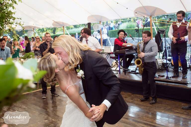 Bride and groom kiss after first dance under tent at One Barn Farm.