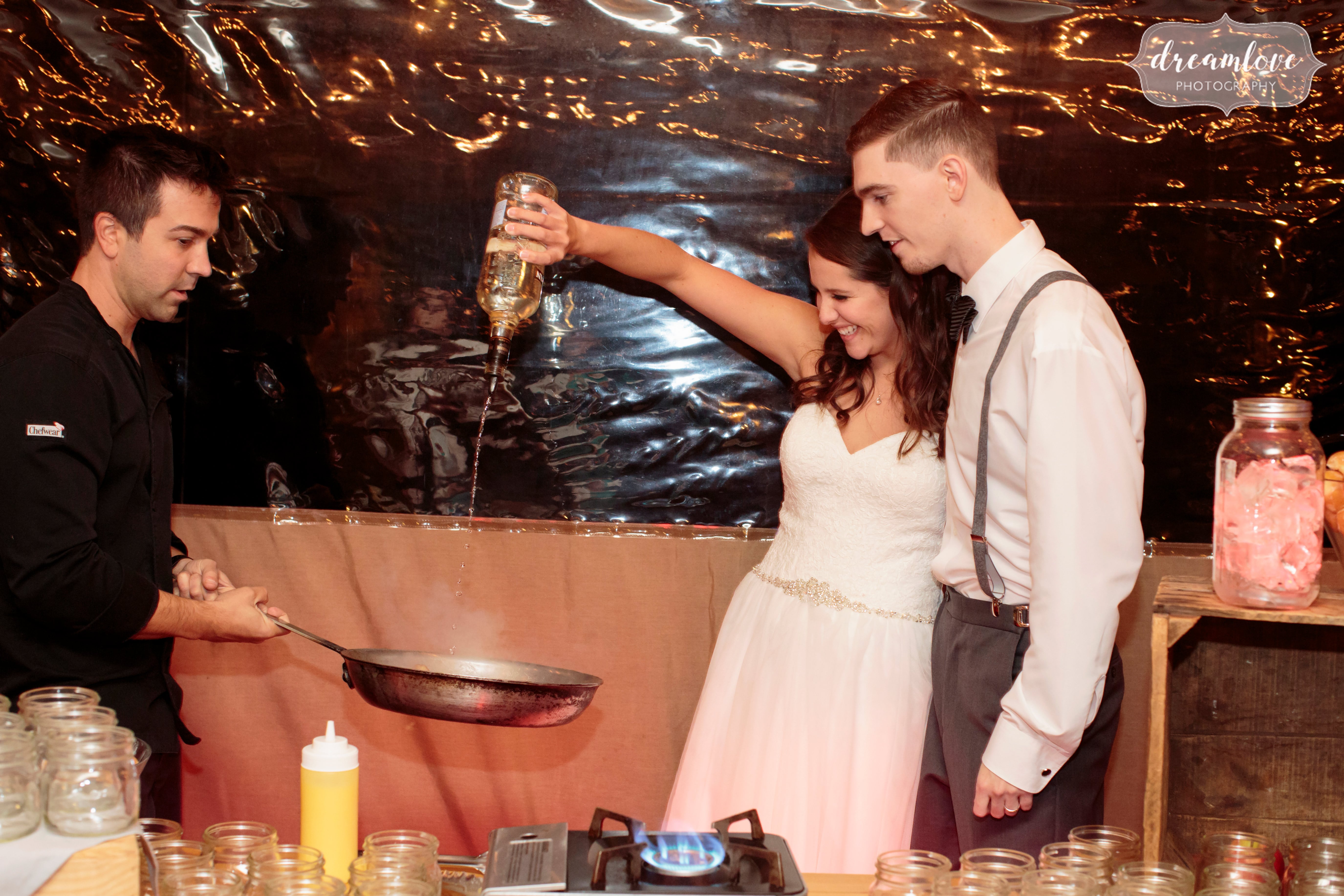 The bride pours oil on a hot pain to fry doughnuts at this rustic wedding reception in November in CT.