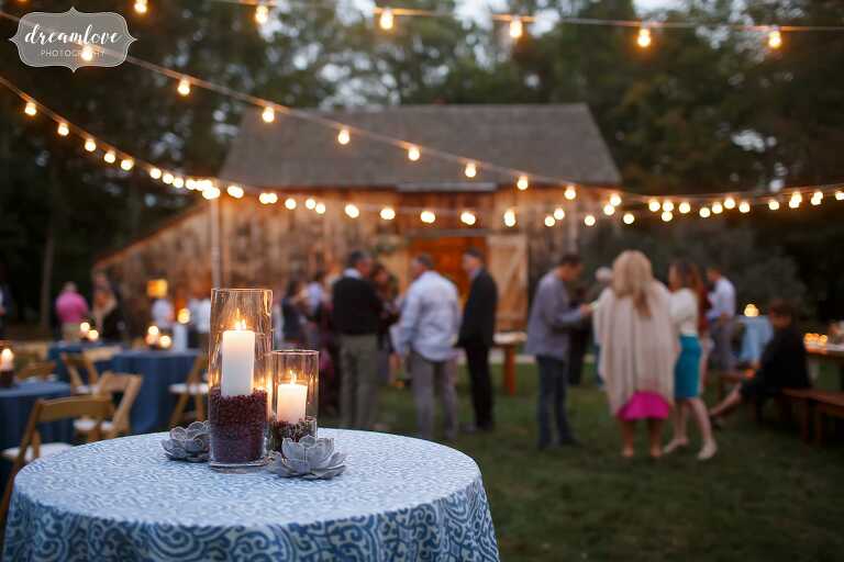 Cafe lights are strung up over tables at this outdoor rehearsal dinner at the Gould Barn.
