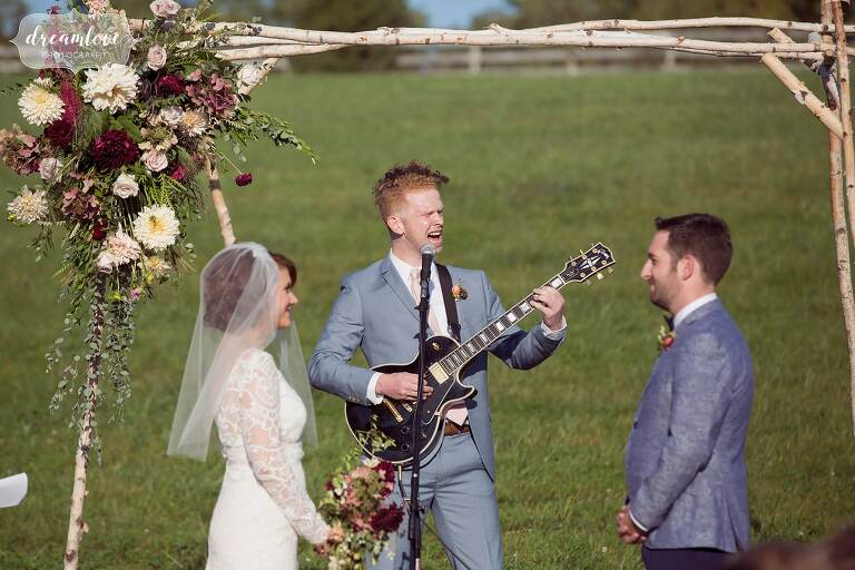 A groomsmen plays the guitar during a musical wedding ceremony at the Barn at Liberty Farms.