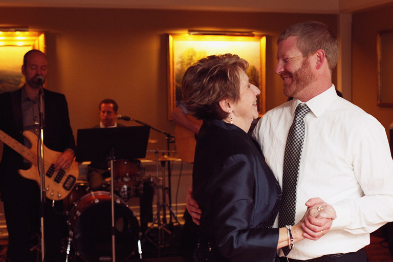 Groom shares a sweet moment with his mom while dancing at a wedding reception. 