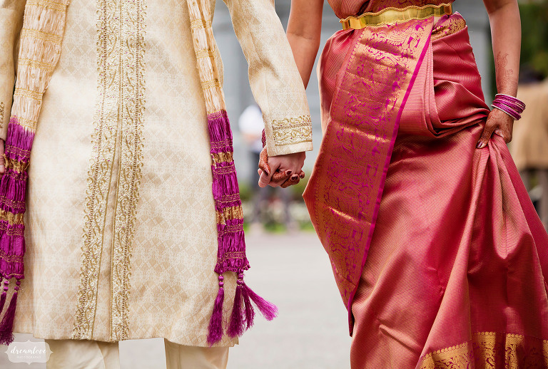 Bride and groom hold hands in Boston Common with traditional Indian saris on for wedding.