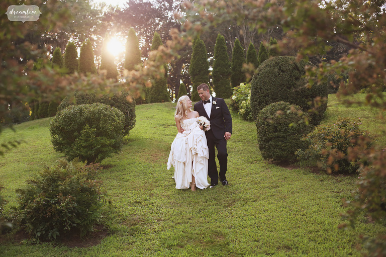 Bride and groom walk down green hill at Glen Manor House wedding venue in Portsmouth, RI.