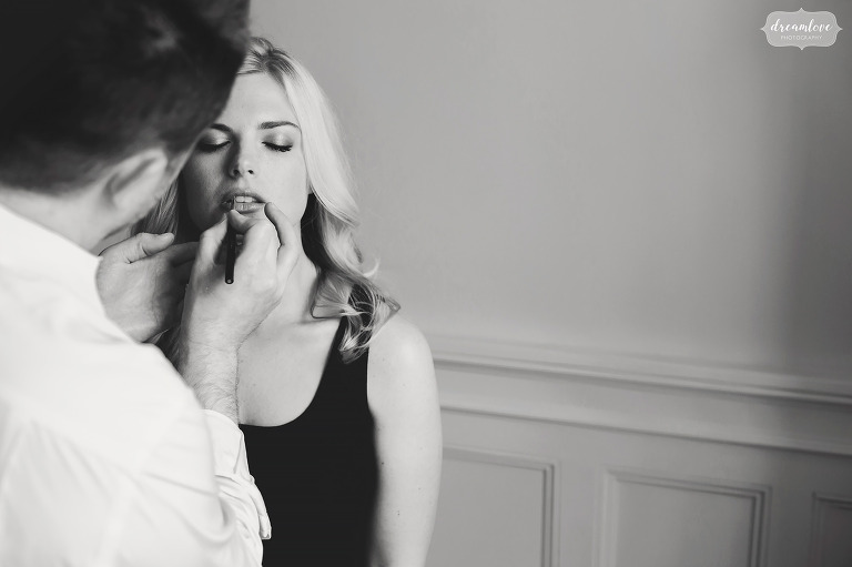 Black and white image of bride having lipstick put on before her Glen Manor House wedding in RI.