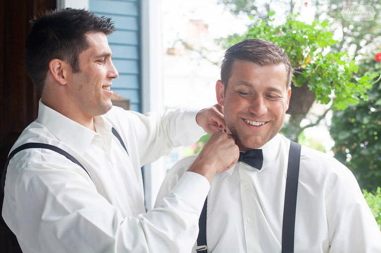 Groomsmen helps groom tie his bow tie in RI.