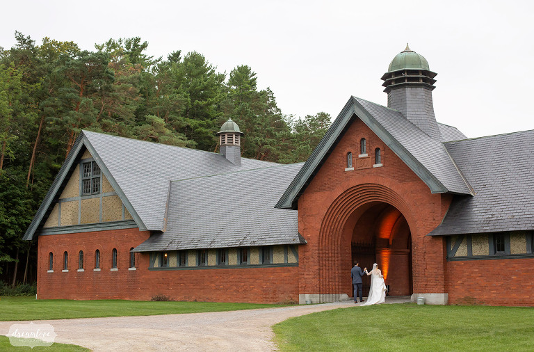 La mariée et le marié marchent sous une arche à Coach Barn dans le Vermont.