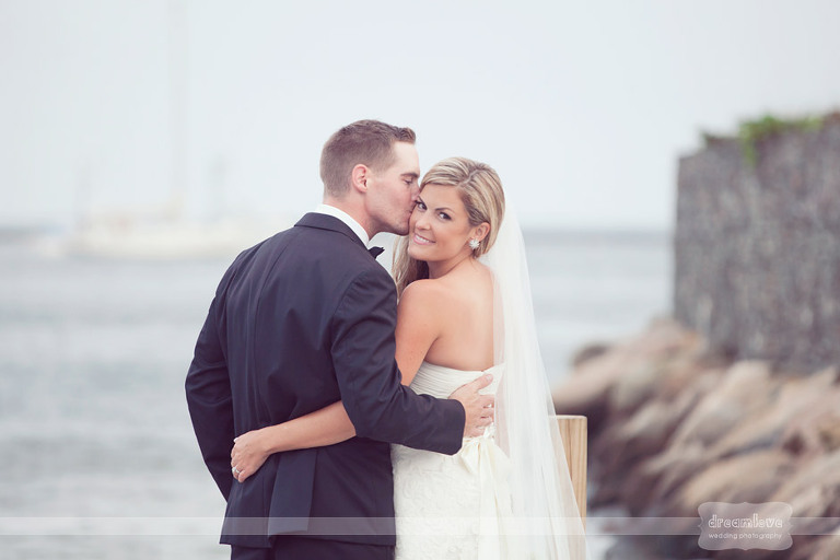 A groom kisses the bride on the cheek at their Wychmere Beach Club wedding. 