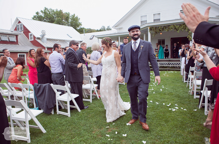 A happy couple high five guests as they recess down the aisle after getting married on the back porch of the Lareau Farm Inn. 