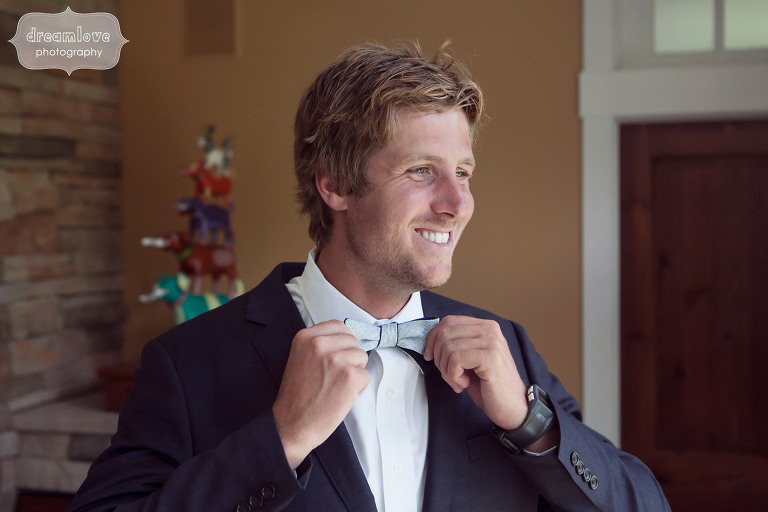 Photo of the dapper groom tying his bowtie at the rustic 1824 House in VT.