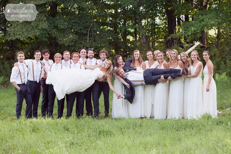 Unique idea for a large wedding party photo to have everyone hold up the bride and groom while they hold hands at the 1824 House in VT. 