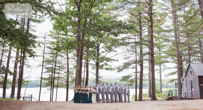 Wedding party of 14 people at the NH camp wedding venue the Woodbound Inn with the lake behind them.
