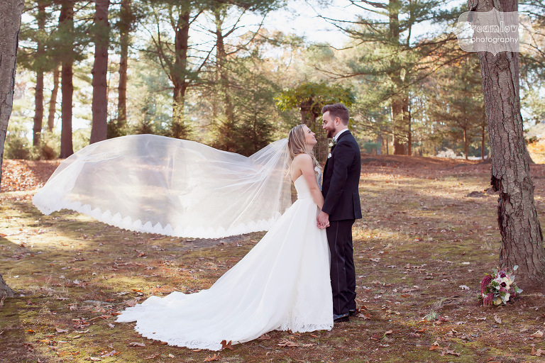 Bride's veil blowing in the wind while kissing the groom at this fall wedding in CT.