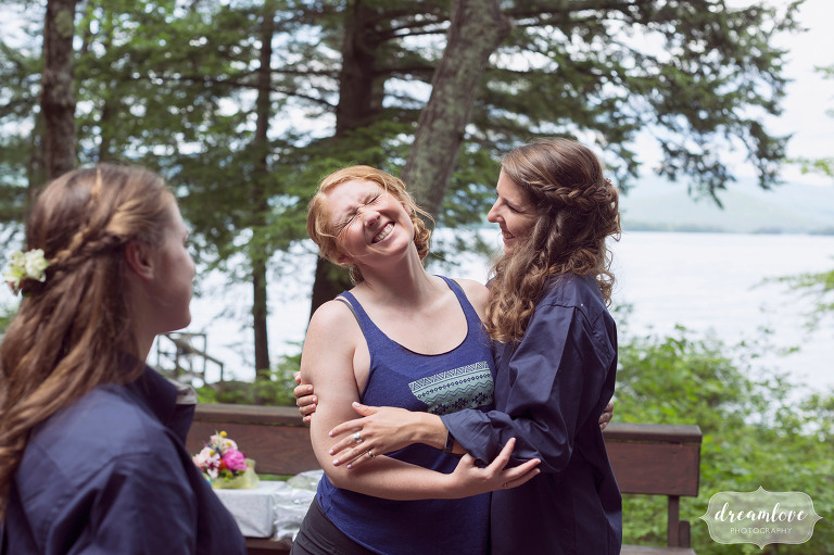 Great documentary wedding photo of the bride laughing with her bridesmaid before her summer camp wedding on Squam Lake in NH.
