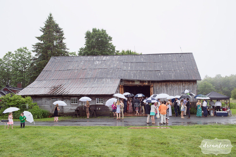 A view of the Comfort Farm barn in the rain as guests gather with umbrellas before the ceremony in Stowe, VT.