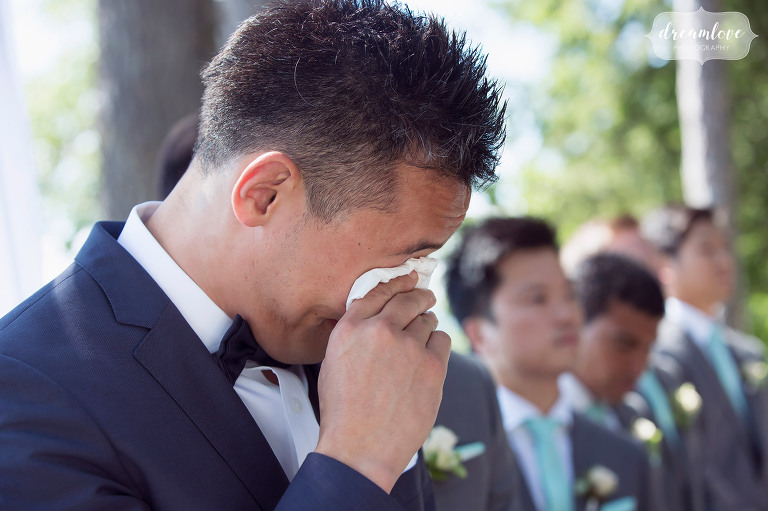 The groom begins to cry when he sees the bride walking down the aisle at this backyard wedding in Wolfeboro, NH on the lake.