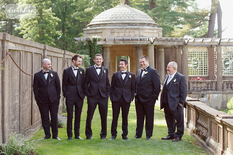 Groomsmen in black suits lined up in the Italian Garden at the Crane Estate.