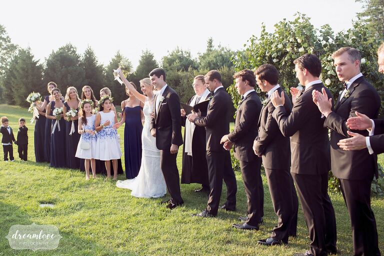 The bride and groom wave to guests at the end of their outdoor ceremony at the Crane Estate.