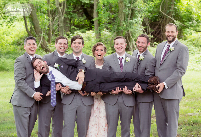 The groomsmen hold up the groom in the air at this NY camp wedding off Long Island.