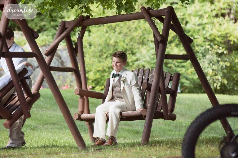 The ring bearer swings on bench at Bishop Farm.
