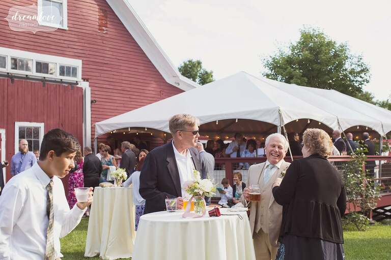 Guests enjoy drinks outside of the Bishop Farm barn during cocktail hour.