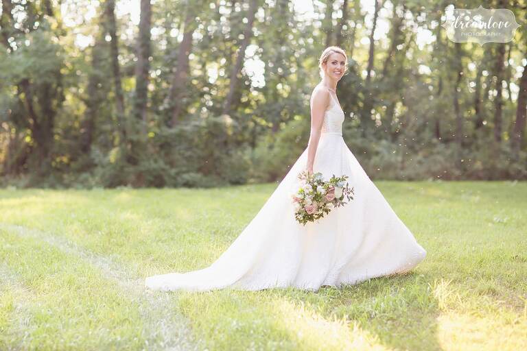 Bride in a Kleinfeld ballroom wedding gown in the field at One Barn Farm.