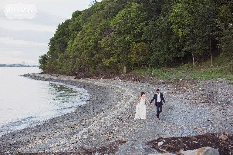 The bride and groom walk along the beach on Thompson Island.