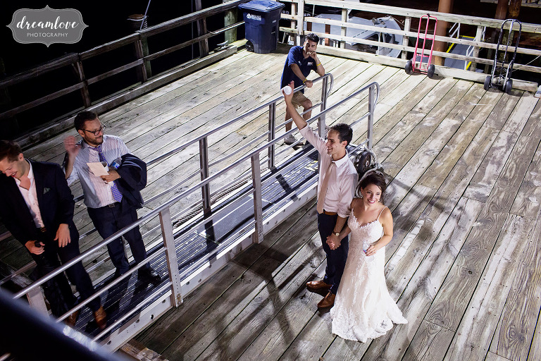 Bride and groom wave goodbye to guests as they load on ferry after Thompson Island wedding.