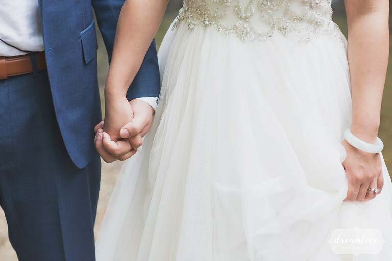 Bride and groom hold hands with monique lhuillier dress.