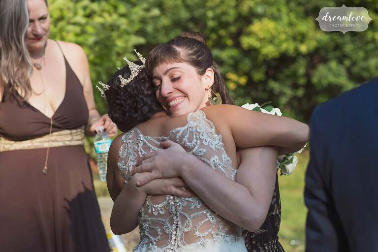 Candid wedding photo of guest hugging bride.
