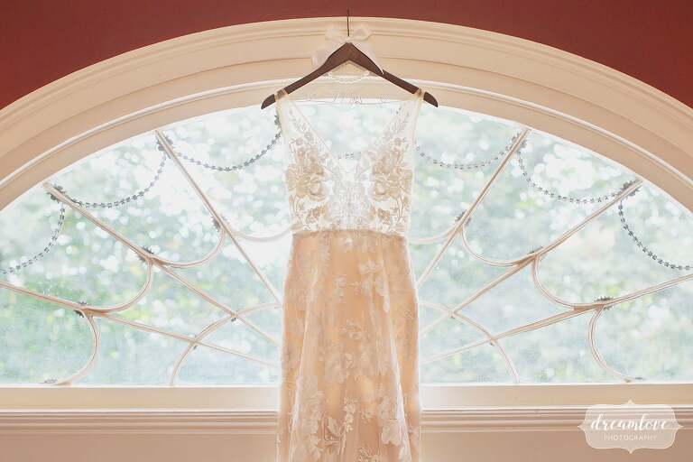 The bride's dress hangs in an antique window at this Bristol, RI estate wedding venue.