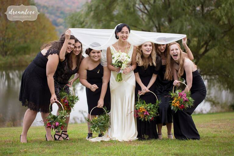Funny photo of the bridesmaids hiding under bride's veil in Roxbury, NY.